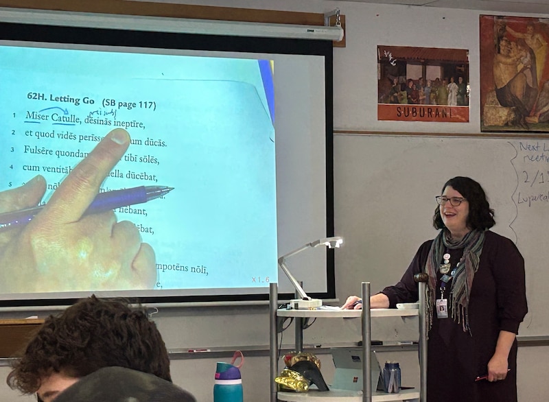 A teacher stands at the front of a high school Latin class.