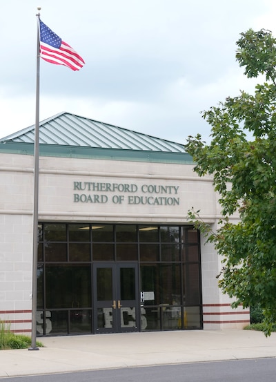 A white building with a green roof and a flag.