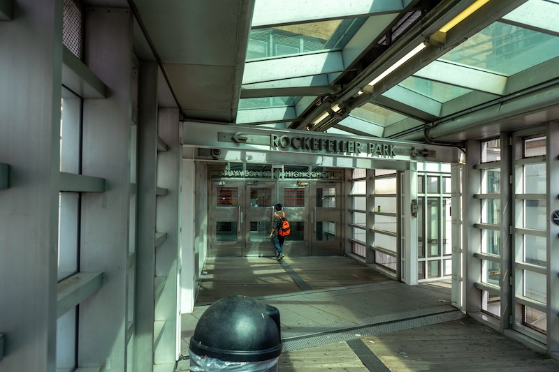 A high school student walks in a glass hallway at a high school.