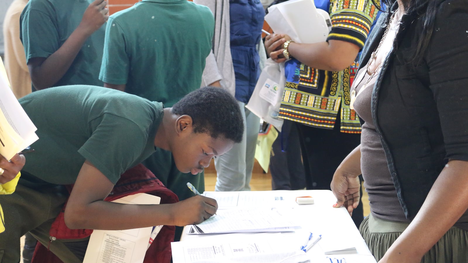 A student signs his name at a high school fair at New Heights Middle School