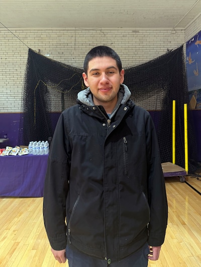 A photograph of a high school student posing for a portrait inside of a school gym.