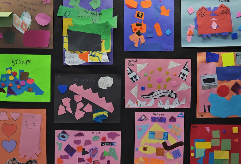 A wall of paper art collages by young students.