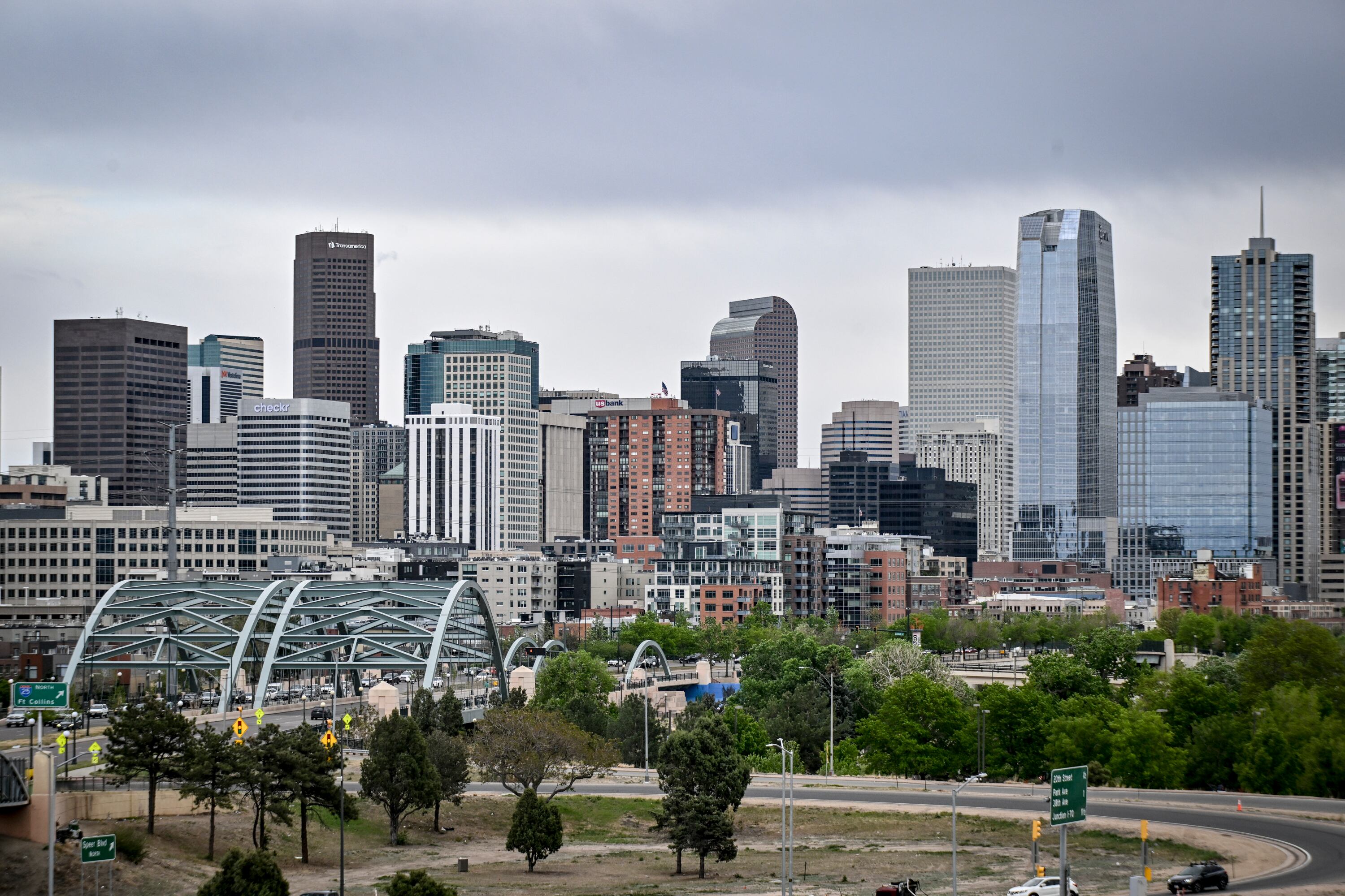 A photograph of Denver's skyline, with a bridge and multiple skyscrapers visible in the distance.