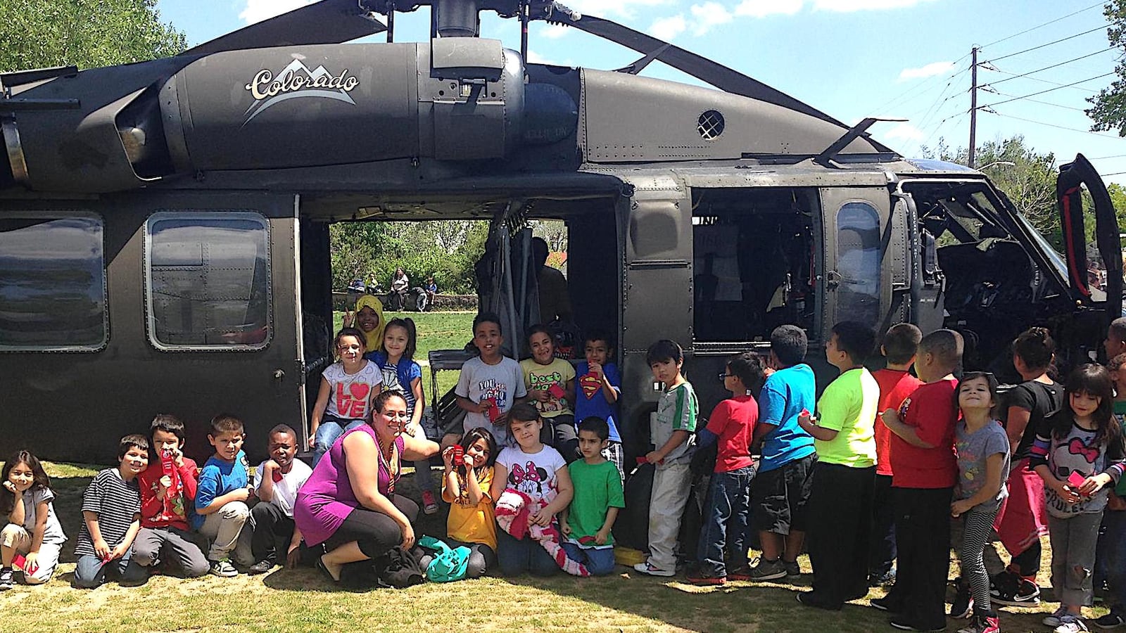Valerie Lovato, a first grade teacher at Denver's Eagleton Elementary, poses with her students in front of a military helicopter that landed on the school's soccer field as part of the "Live Drug Free!" initiative.
