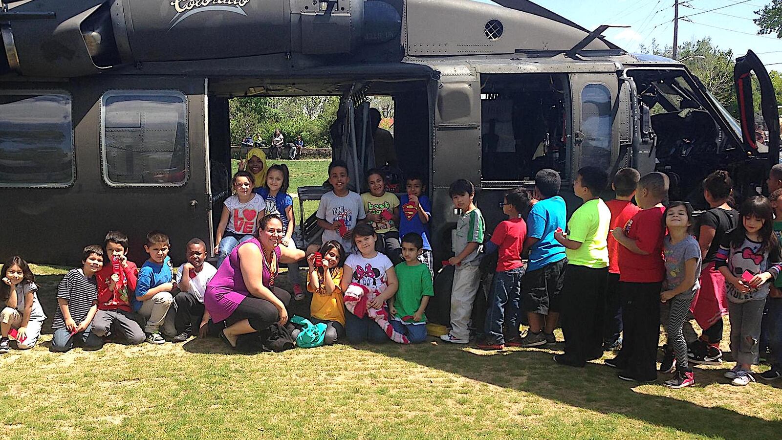 Valerie Lovato, a first grade teacher at Denver's Eagleton Elementary, poses with her students in front of a military helicopter that landed on the school's soccer field as part of the "Live Drug Free!" initiative.
