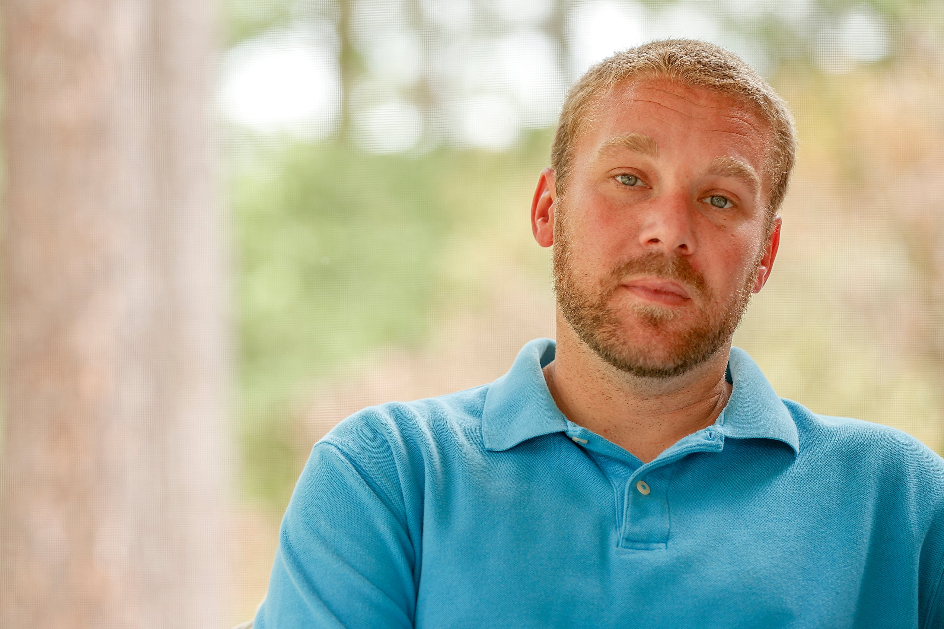 man in turquoise shirt with blond hair and facial hair