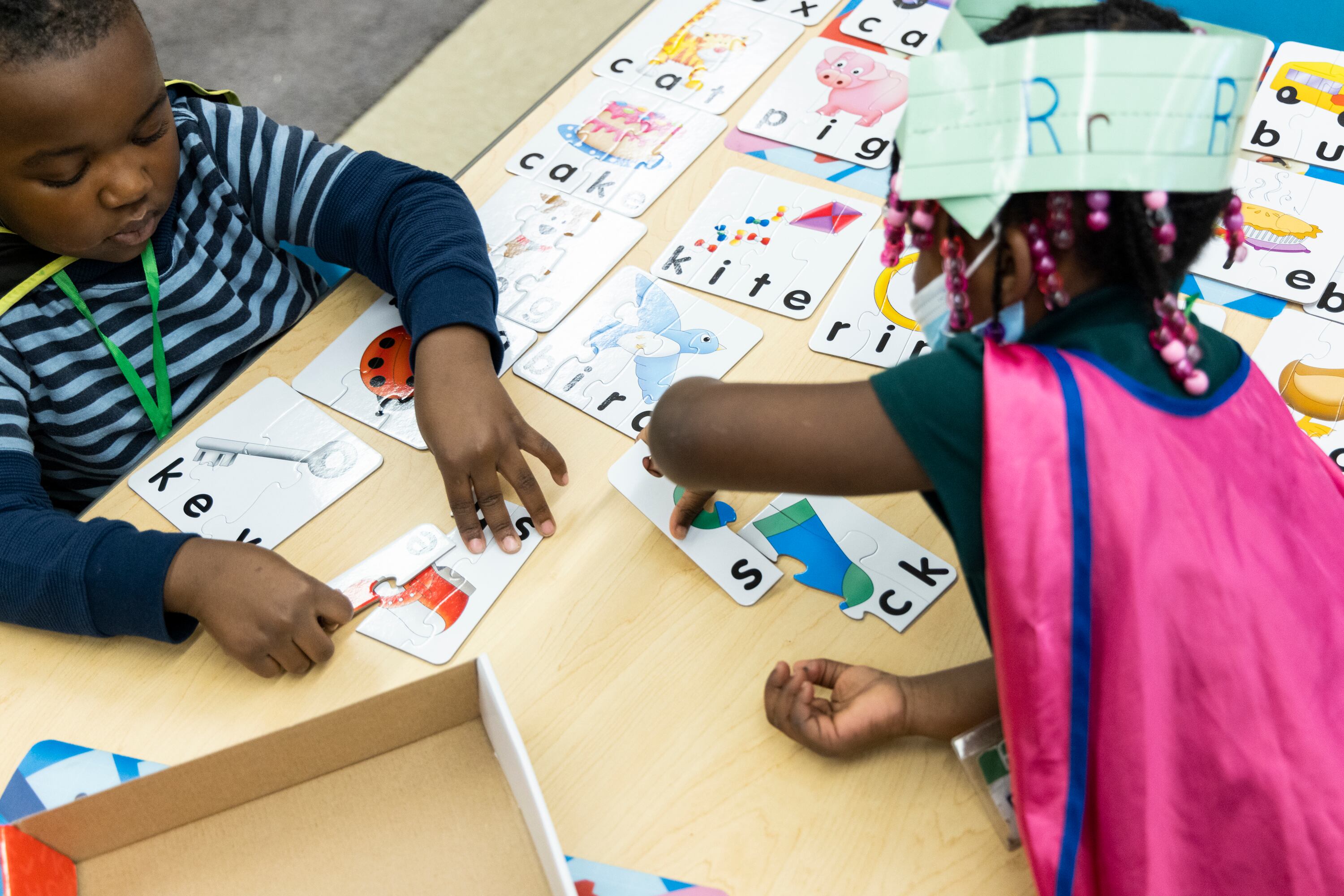 Two students work at a wooden table with word puzzles.