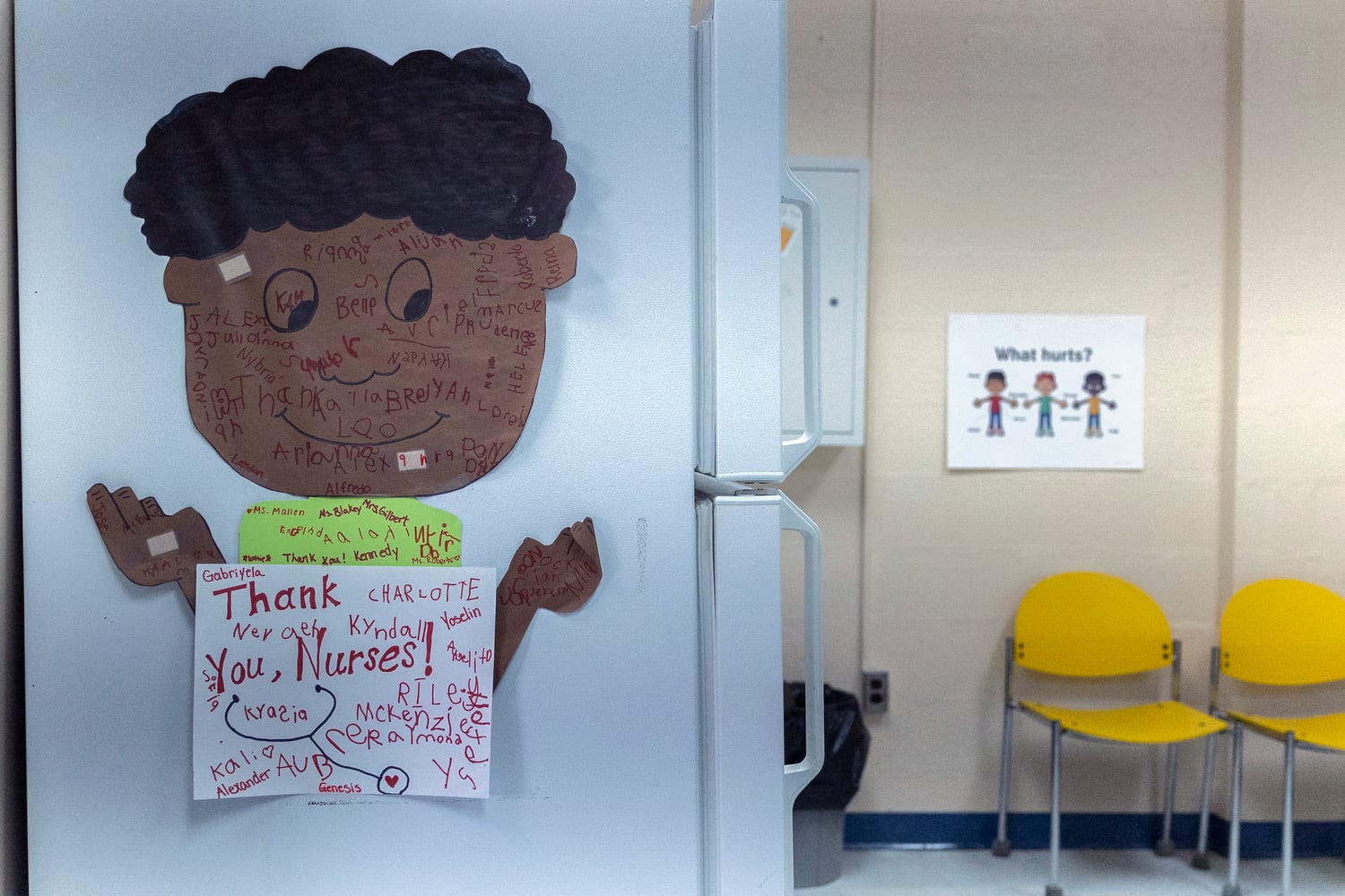 A poster of a little boy with a sign saying “Thank you nurses!” is on the side of the refrigerator in the nurse’s office of an elementary school.