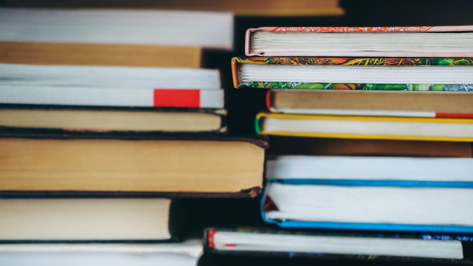 Two stacks of books in a row on a table.