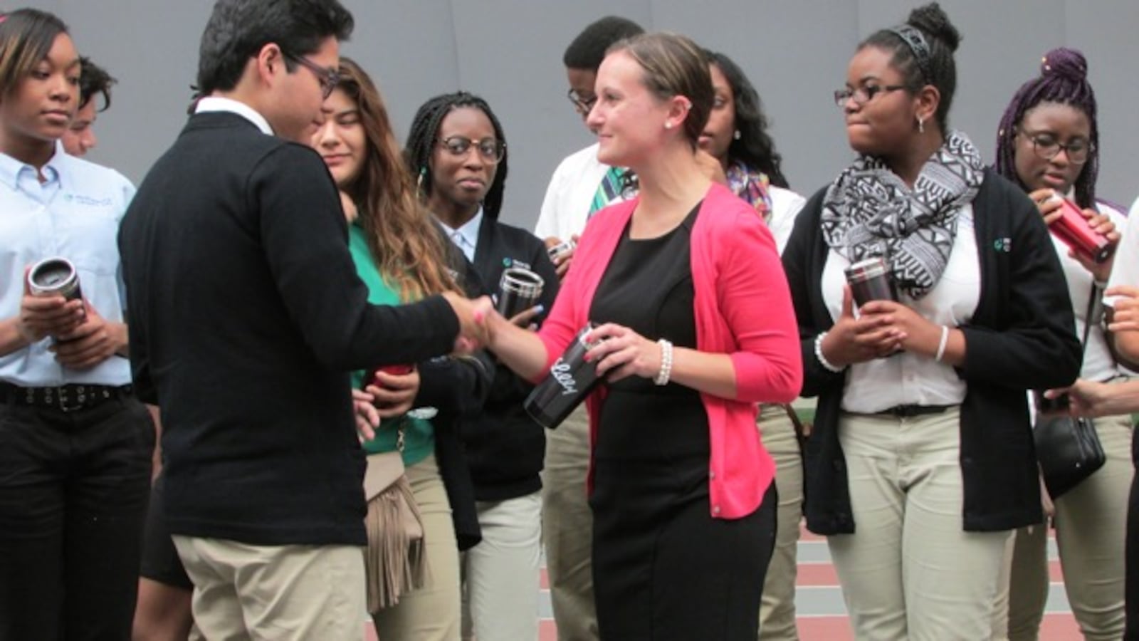 Monica Riddle of Eli Lilly & Co. welcomes  Junior Omar Ramirez for a work-study job this year. Other students selected by the company gather behind them on stage at Draft Day for Providence Cristo Rey High School at the University of Indianapolis.  The other students pictured are (left to right) senior Marlene Amador, Junior Lindsey Dewalt and Freshman Leairra Carter.
