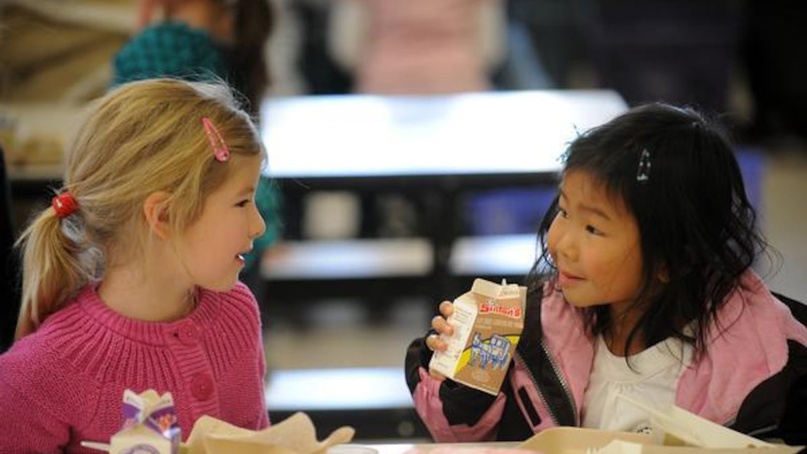 Six-year-olds Lilly Clark, left, and Zoe Burger talk during lunch at Lincoln Elementary School in Denver.