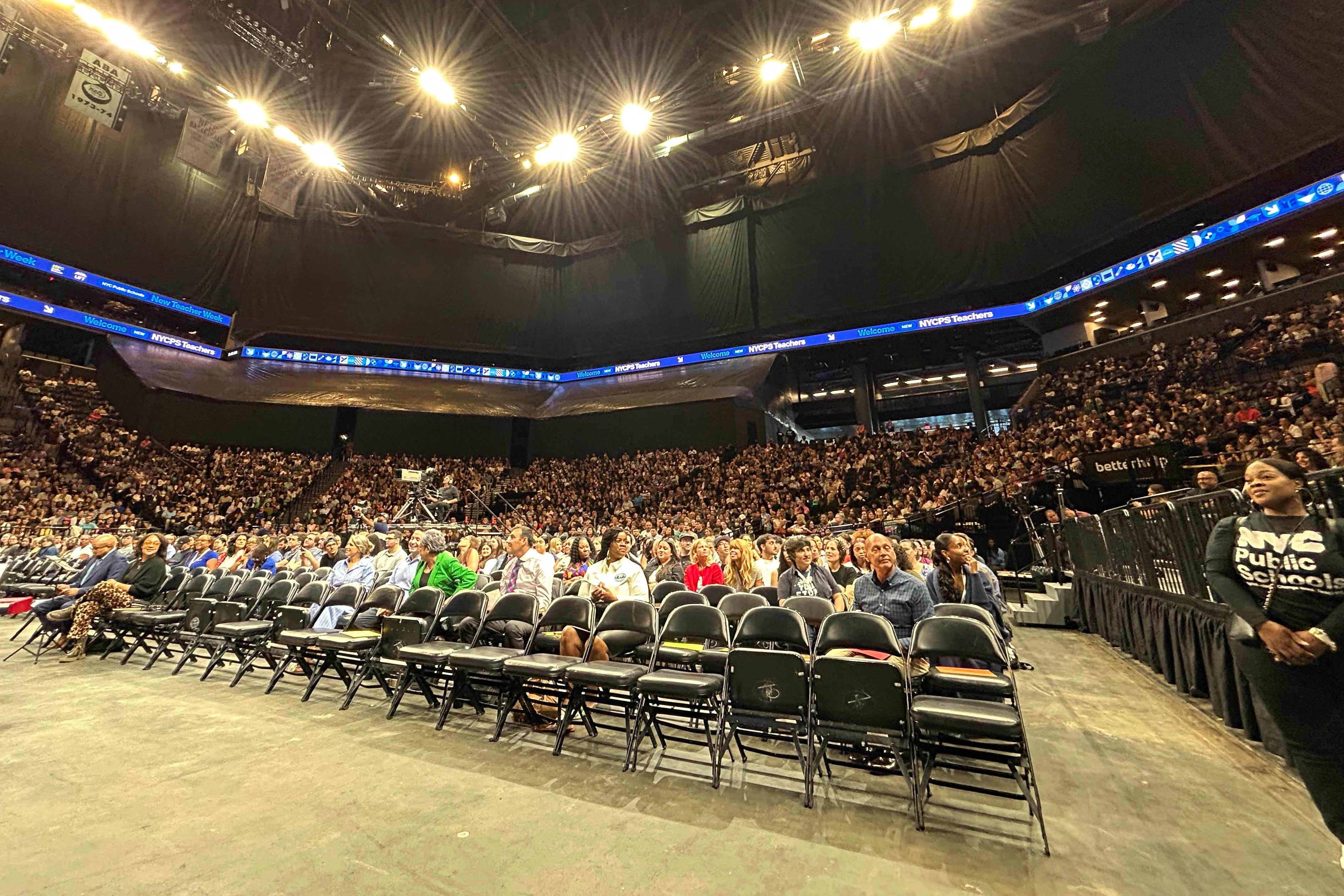 A photograph of a giant crowd of adults sitting inside of a large stadium.