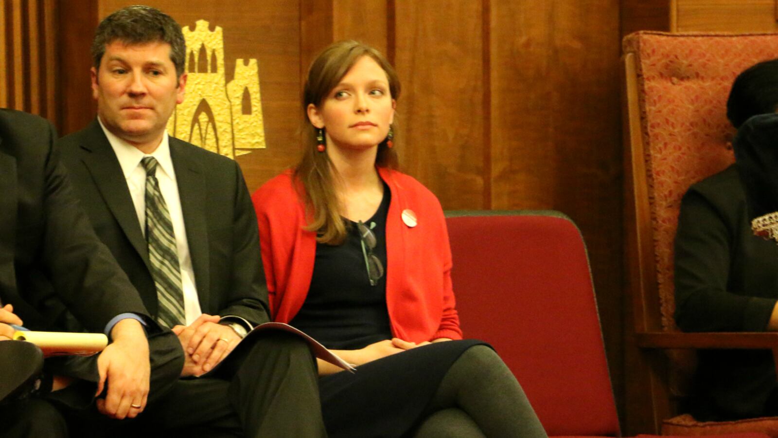 A man, left, and a woman, right, sit in red chairs.