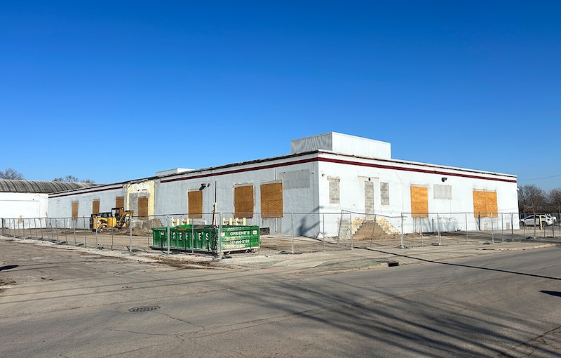 A white building with boarded-up windows.