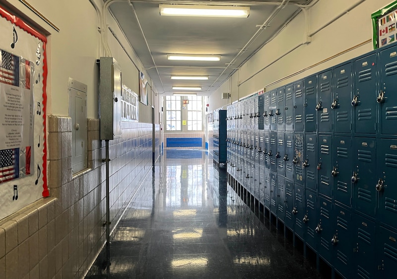 A well-lit hallway with blue lockers lining the wall on the right.