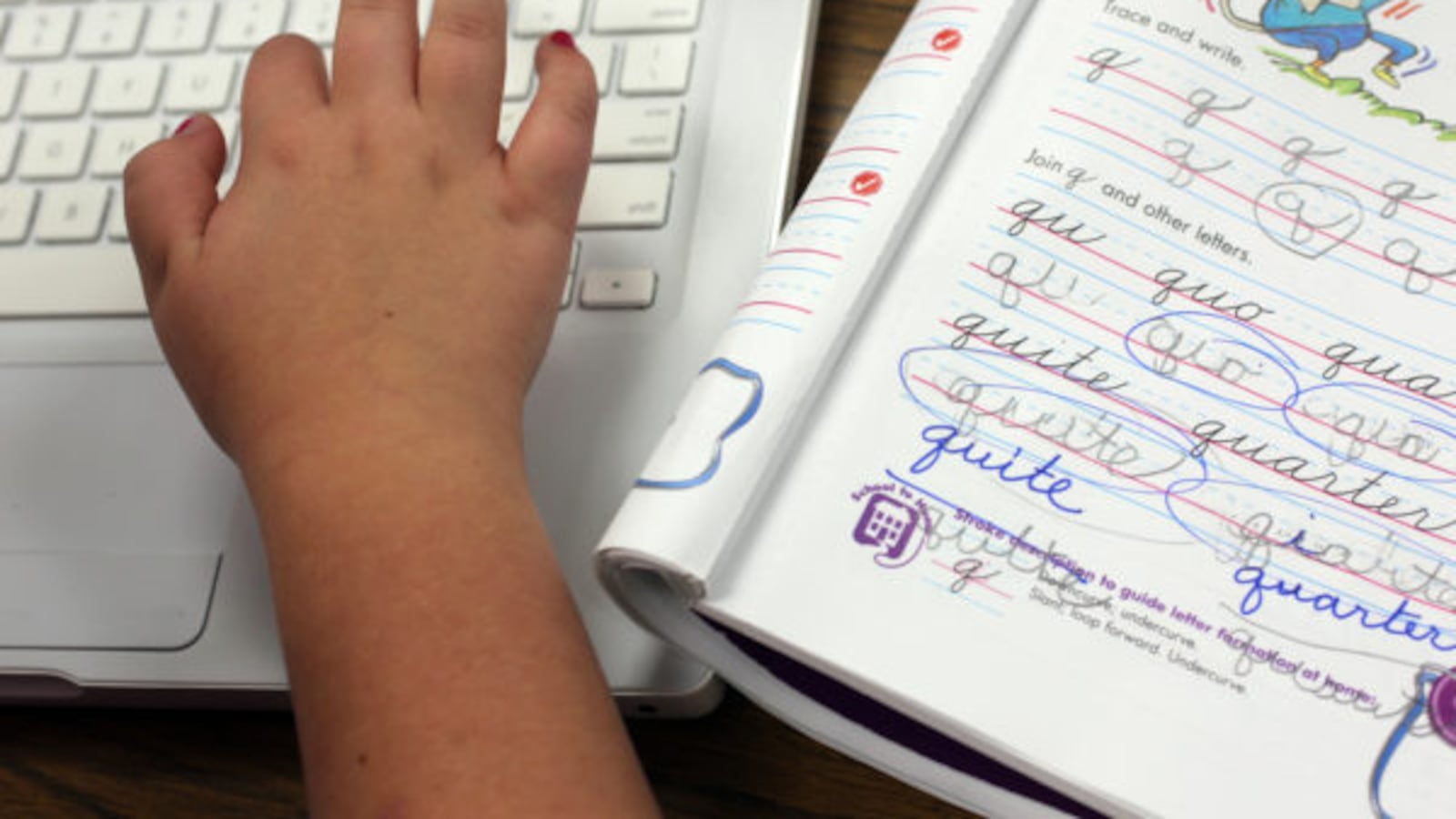 A student types on a laptop after finishing a cursive lesson.