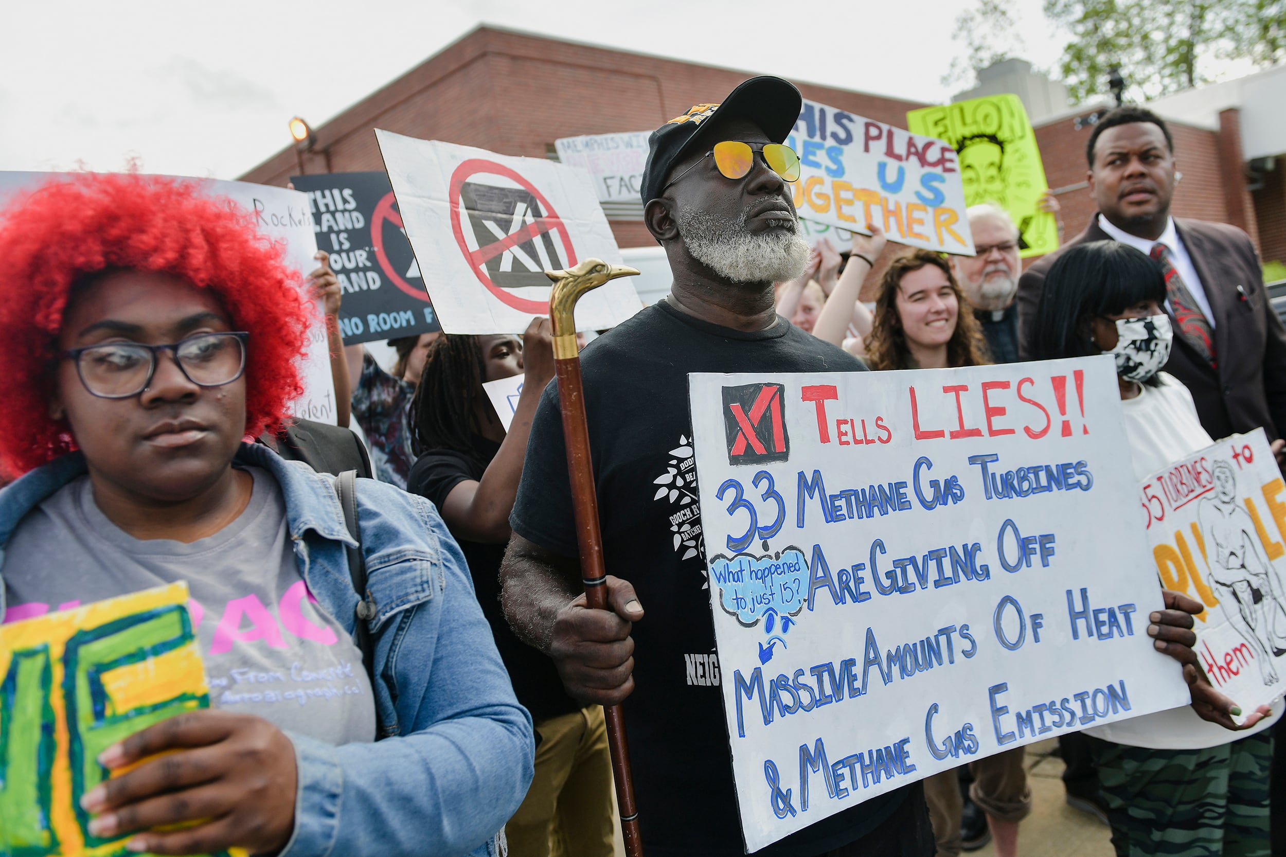 A photograph of a group of protestors holding large signs outside.