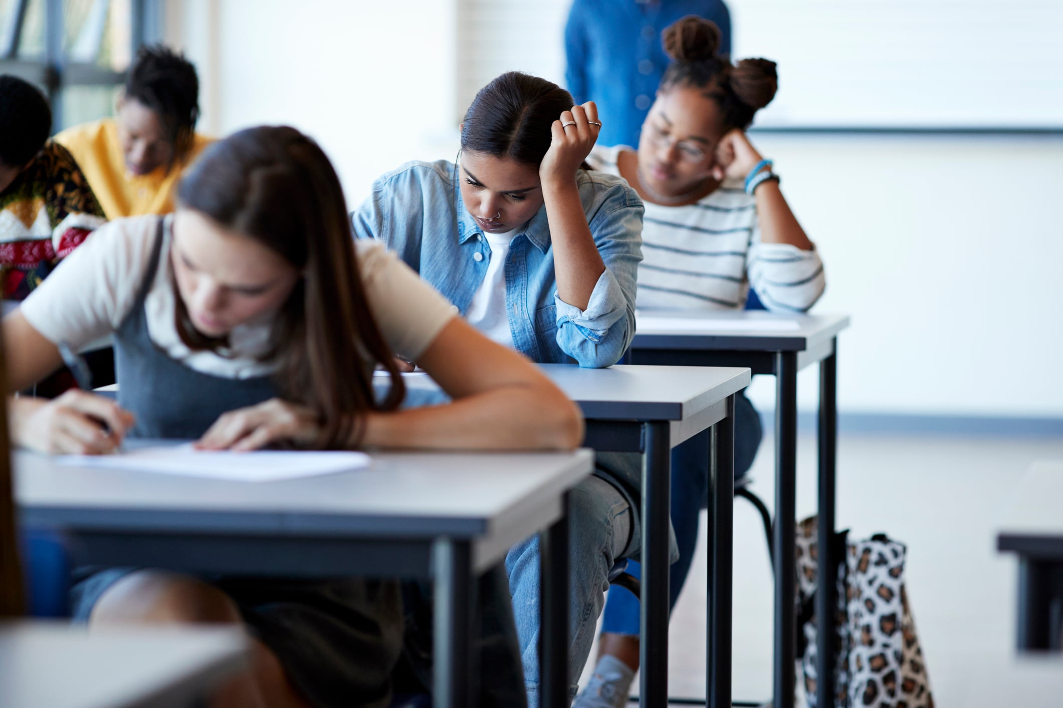 Students take a test at their desks in a classroom.