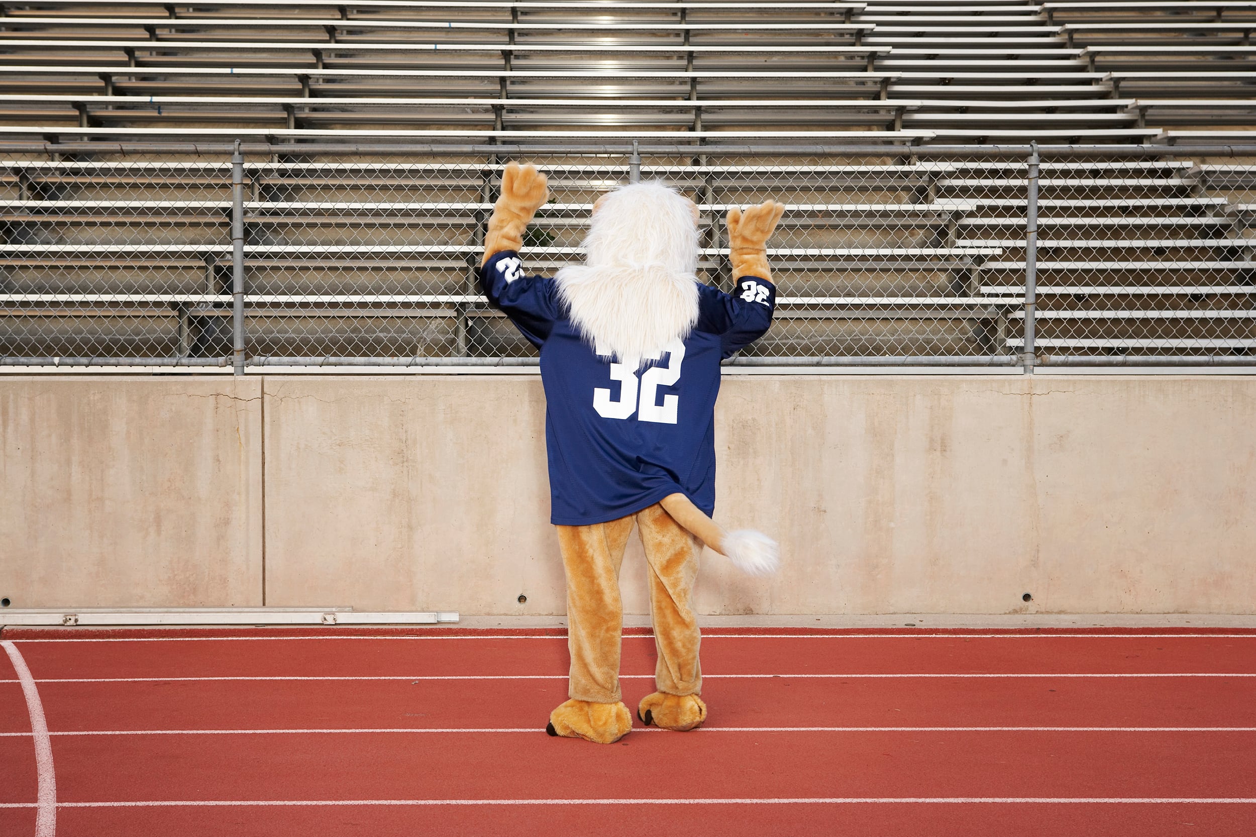 A photograph of a school mascot on running track, rear view.