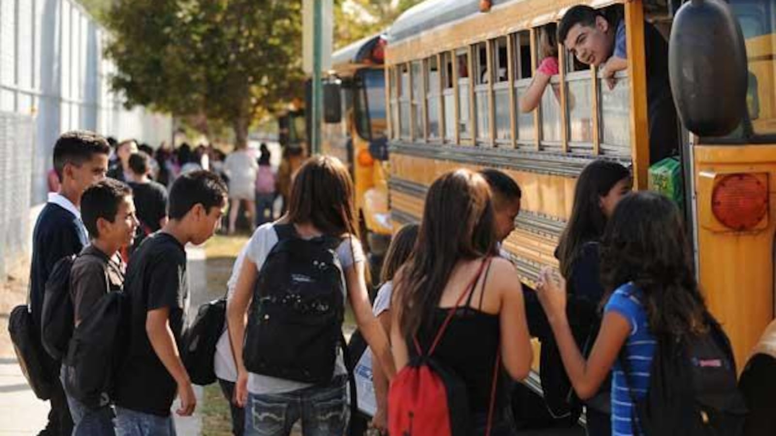 Rosando Martinez, 12, hangs his head out a school bus window and talks to friends after school at Grant Beacon Middle School in Denver.
