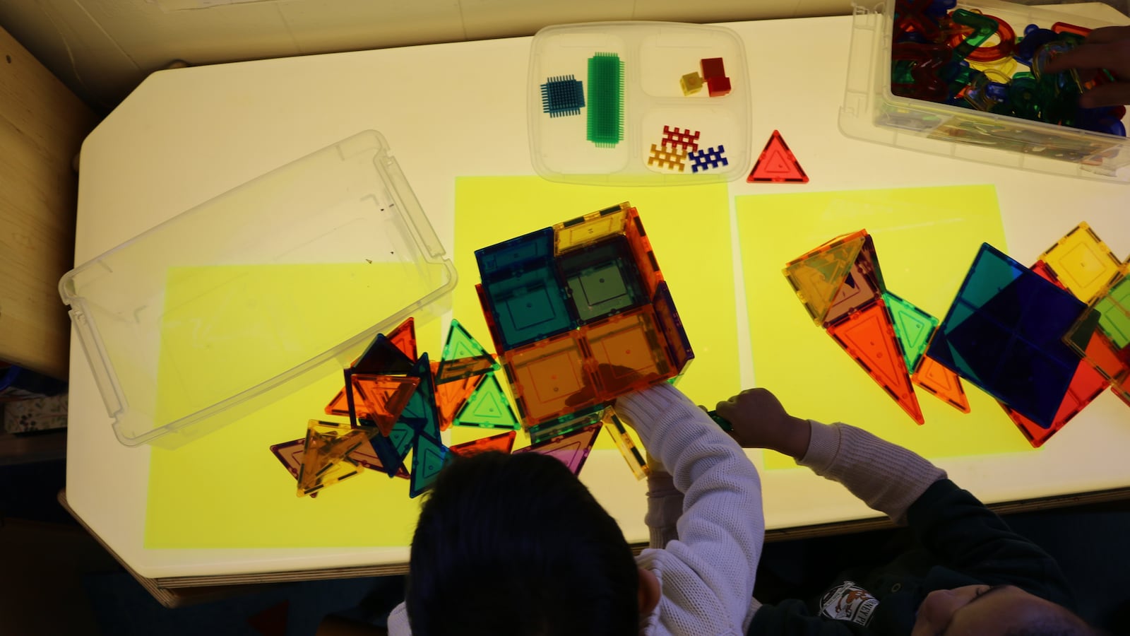 Pre-K students at P.S. 69 Journey Prep play with magnetic blocks on a light-up table.