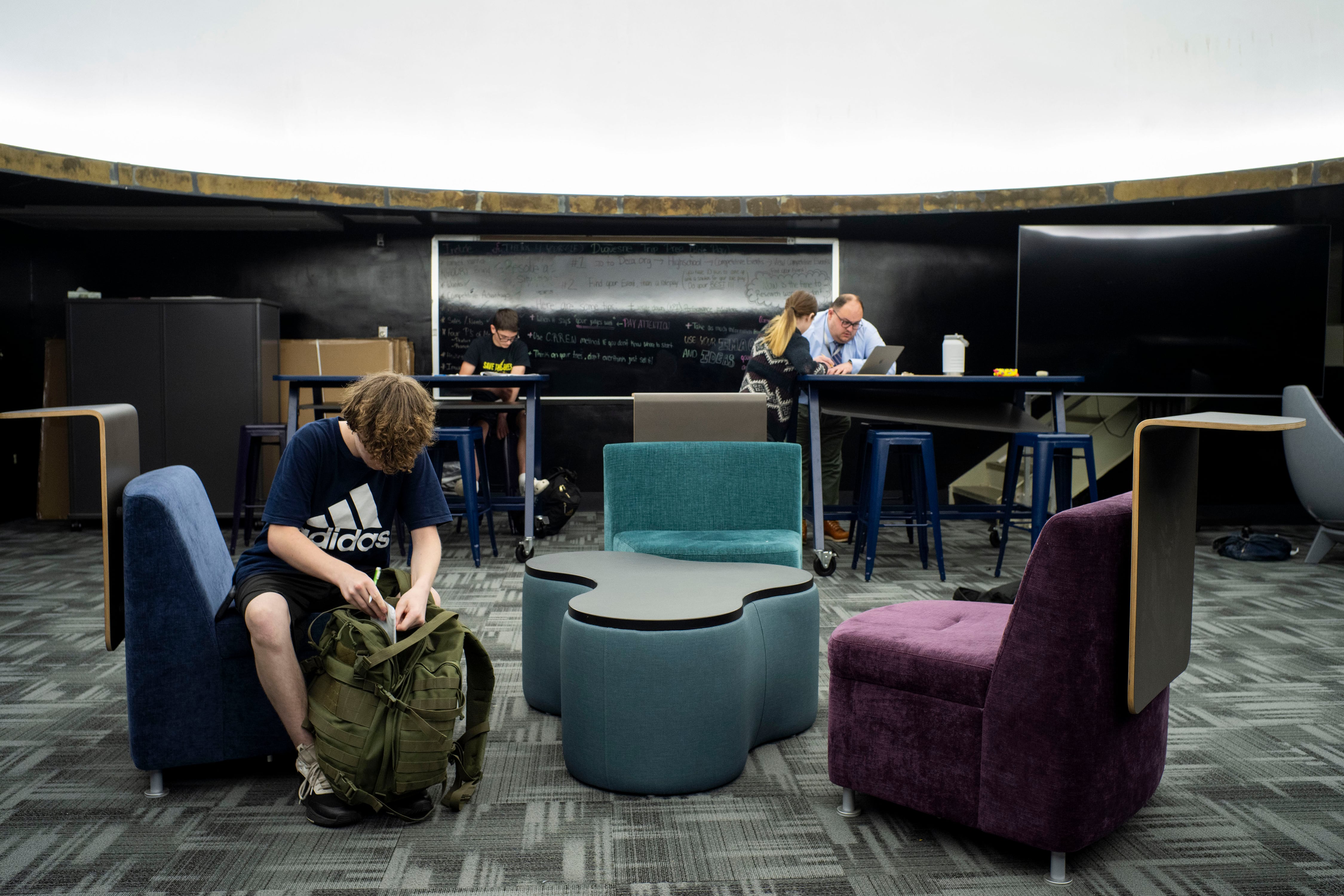 Three students and an adult teacher work during class in the planetarium.