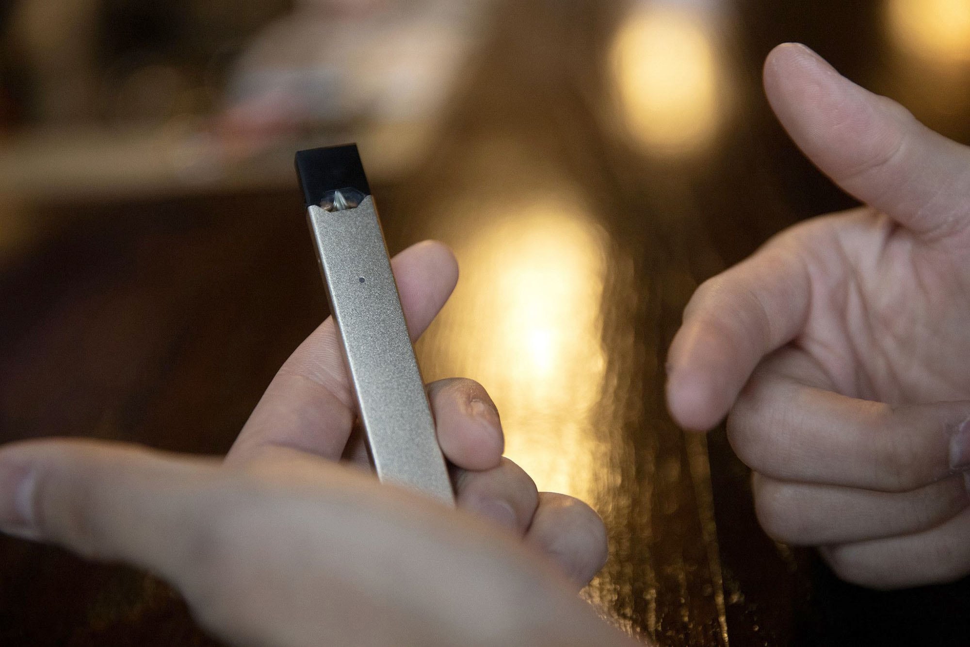 A pair of hands holds a vaping device.