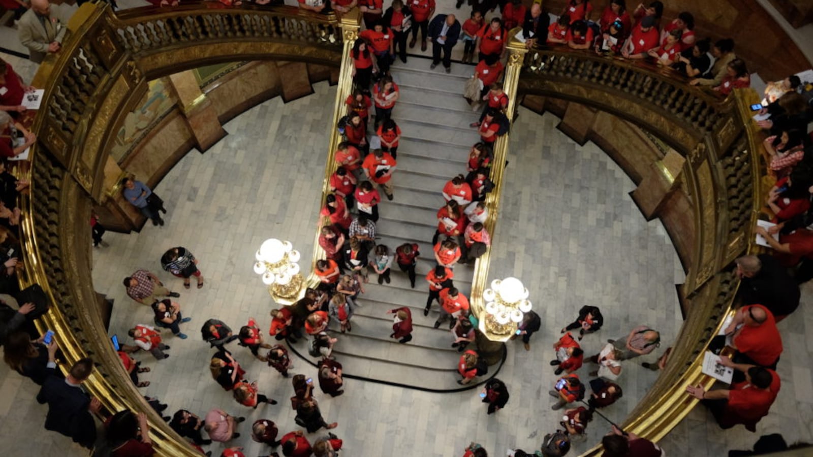 Teachers in red gather in the rotunda of the Colorado State Capitol in 2018. They line the stairway and are seen from above.