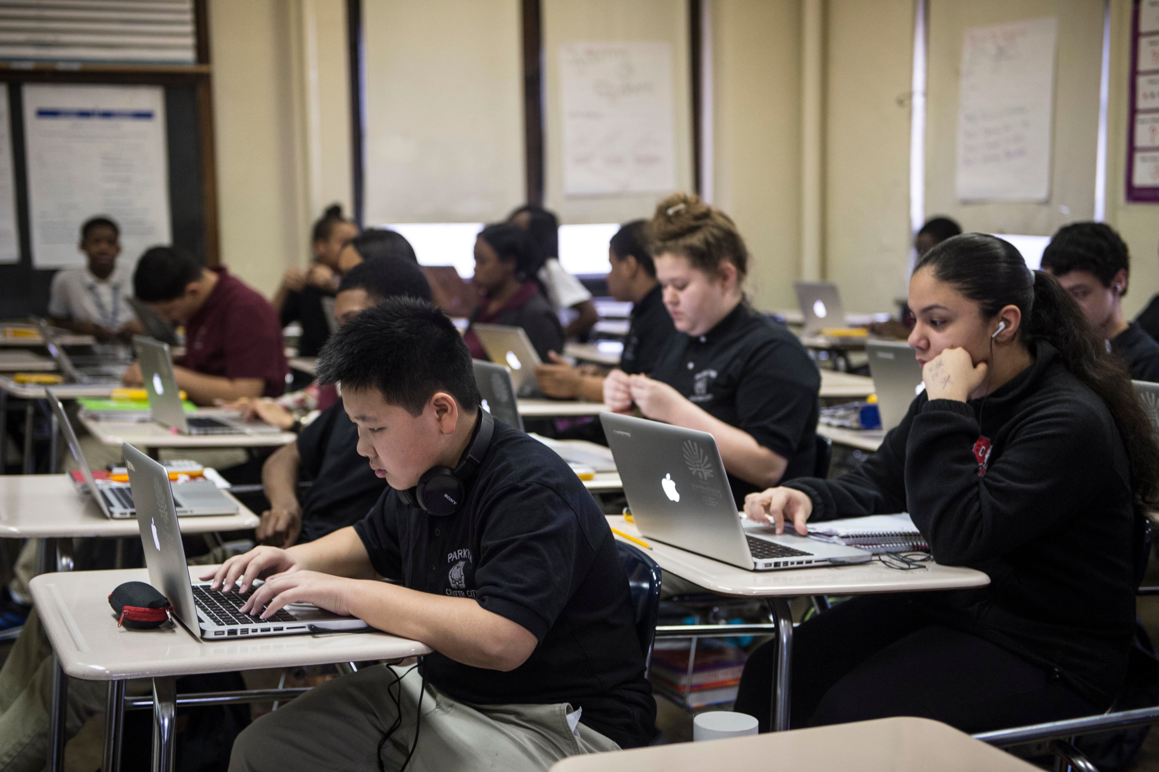 A classroom full of high school students working at individual desks with laptops.