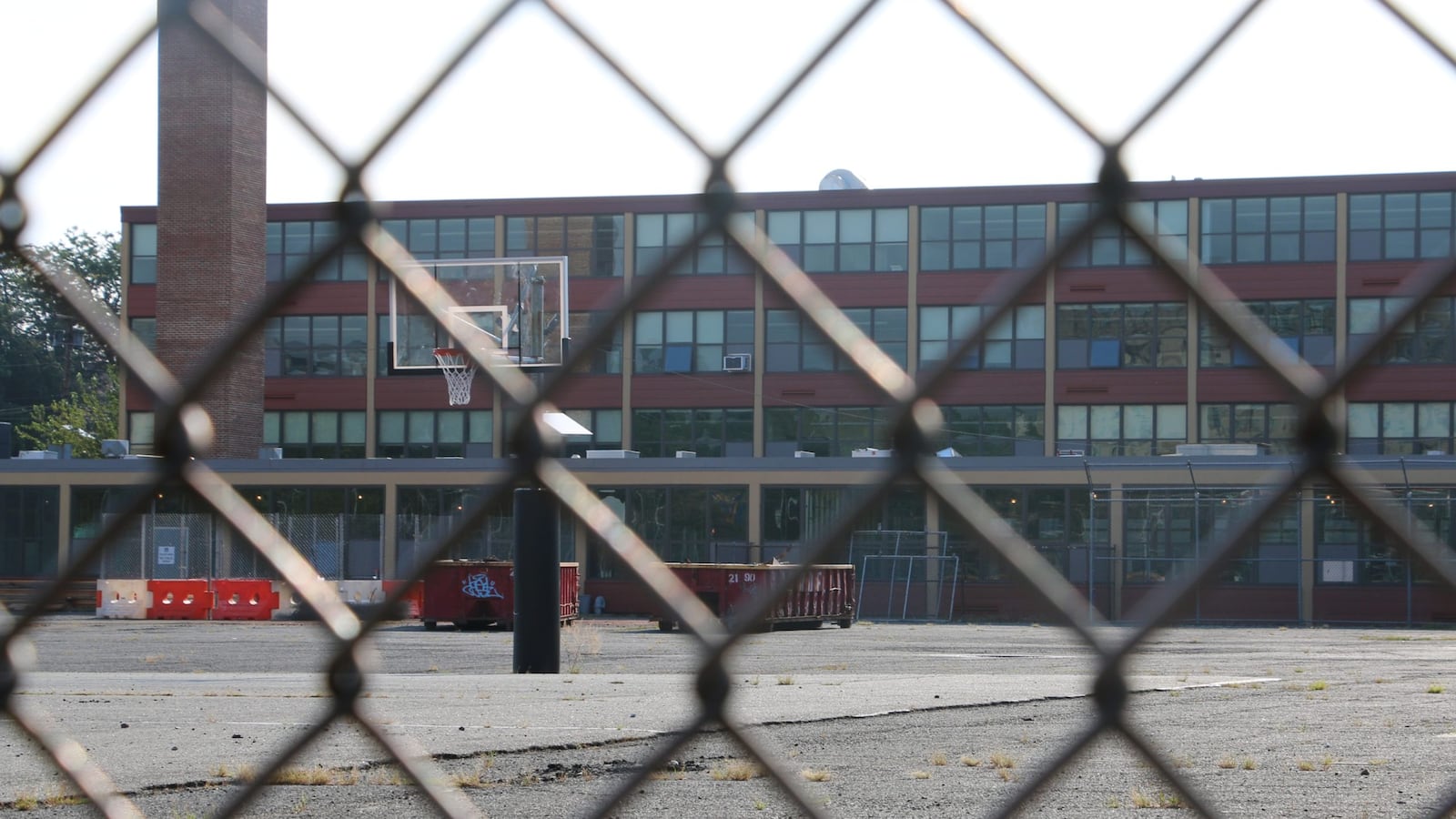 A building is seen behind a chain-link fence.