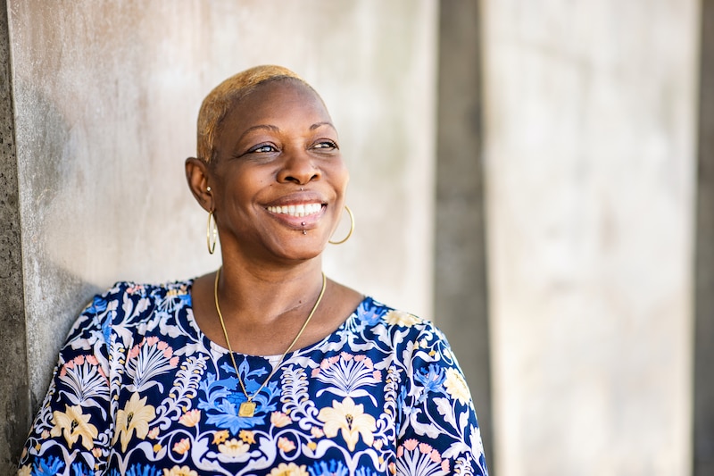 A woman in a patterned top smiles in a portrait.