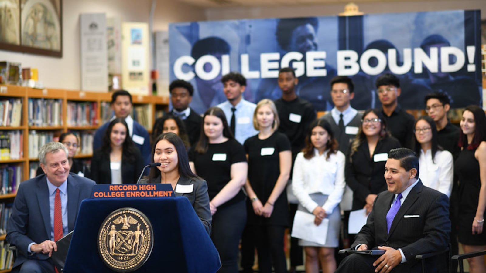 At a press conference about college enrollment, Mayor Bill de Blasio and Chancellor Richard Carranza listen to an alum of High School of Telecommunication Arts and Technology talk about her experience enrolling in college.