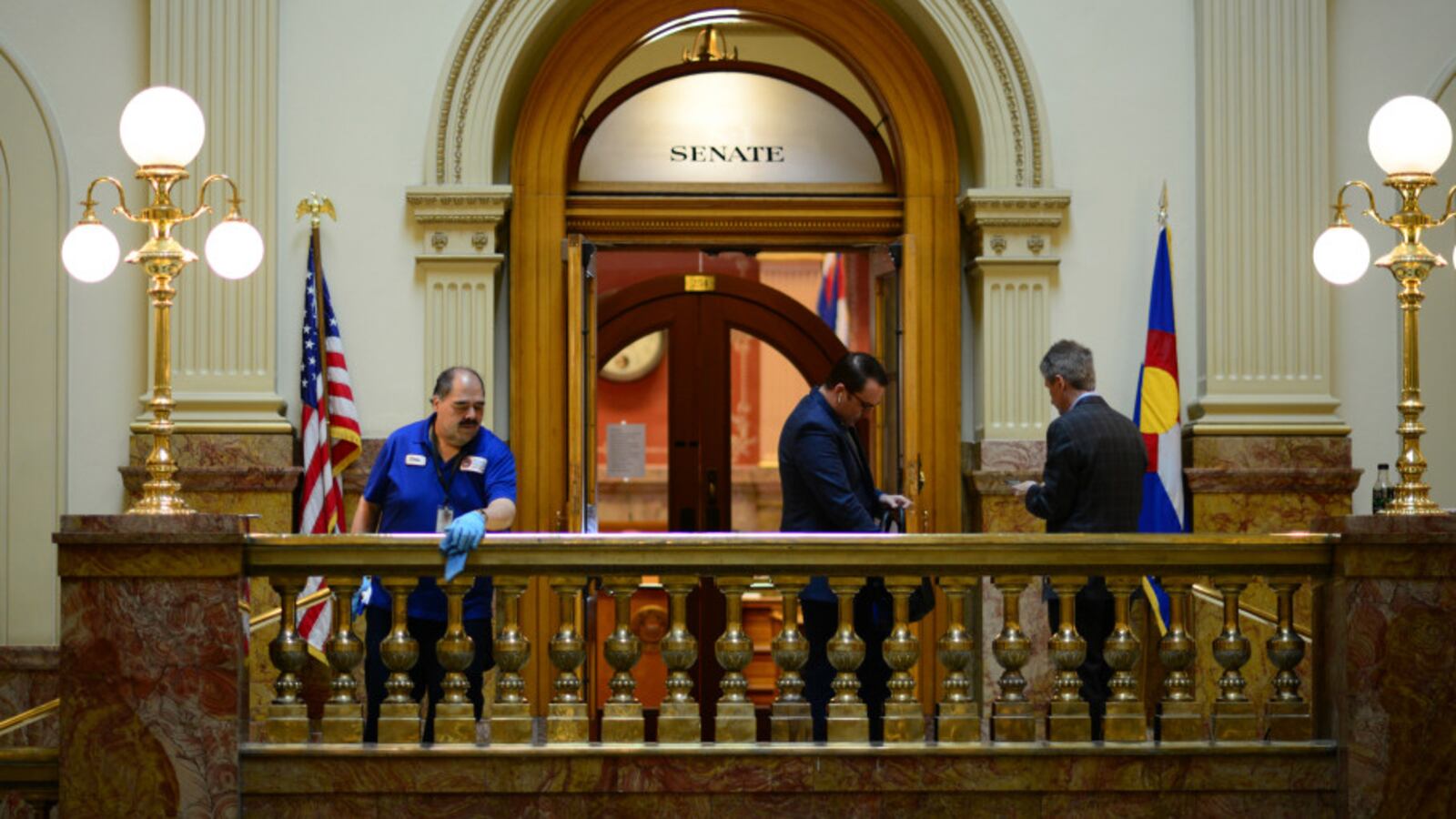 Janitor Chris Martinez, left, wipes down the handrails outside the Senate in the Colorado State Capital building in Denver, Colorado on March 13, 2020.