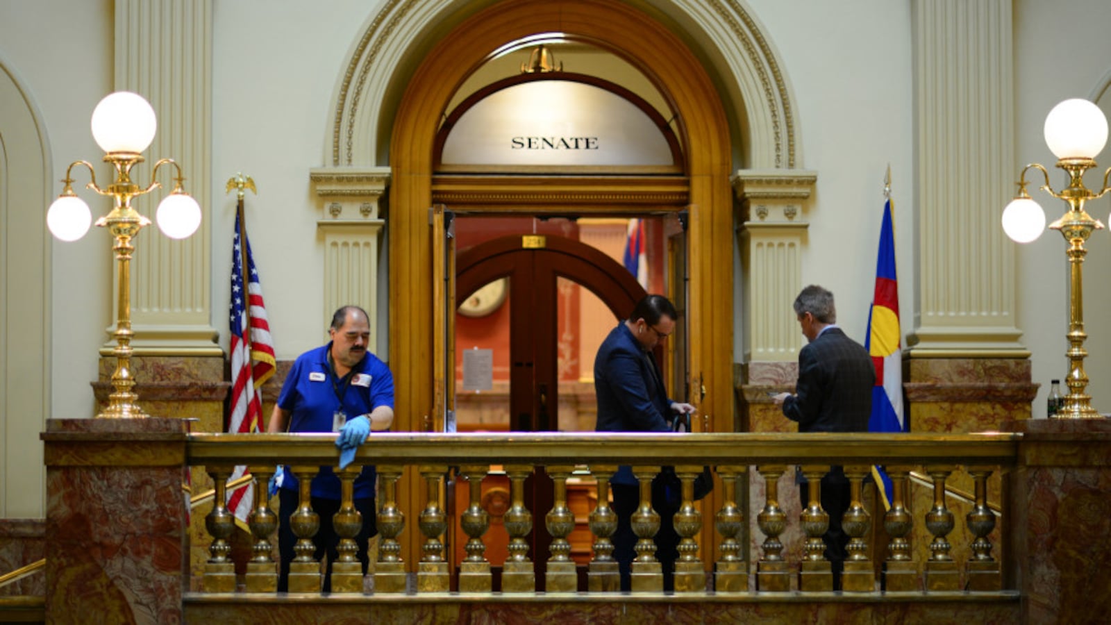 Janitor Chris Martinez, left, wipes down the handrails outside the Senate in the Colorado State Capital building in Denver, Colorado on March 13, 2020.