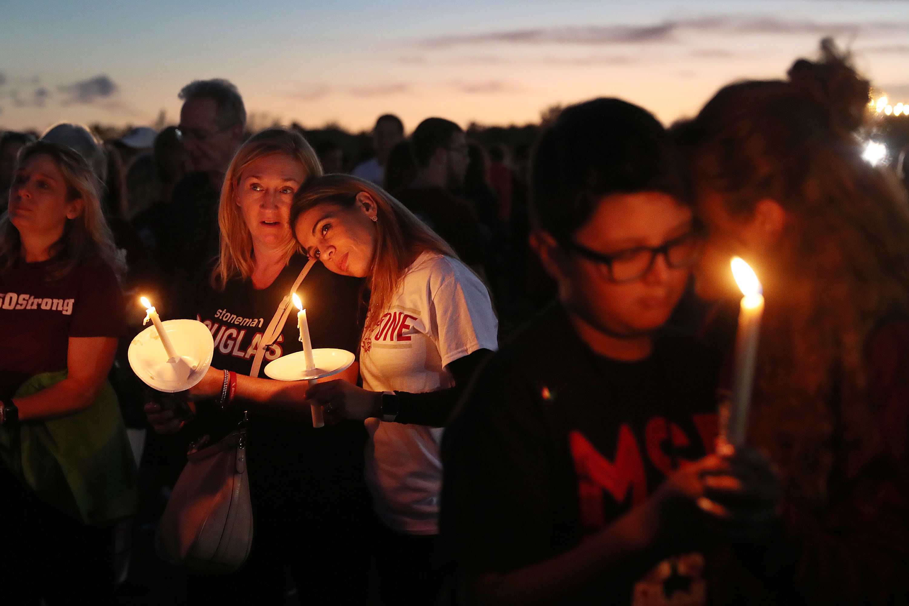 Parents hold their children during a candlelight vigil for victims of a school shooting.