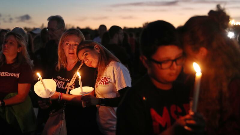 Parents hold their children during a candlelight vigil for victims of a school shooting.