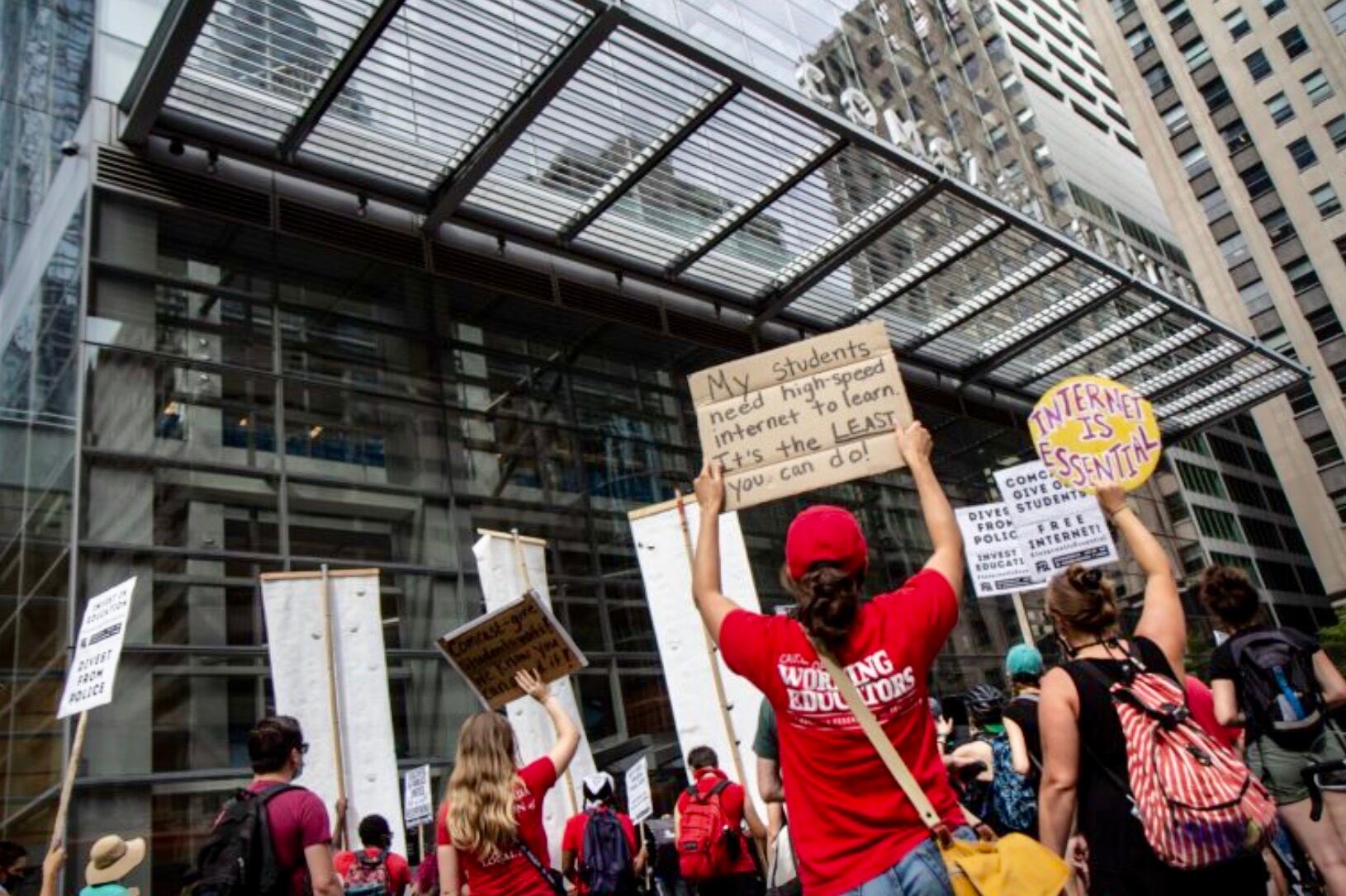 Group of protestors holding signs outside the Comcast Center in Philadelphia, PA.