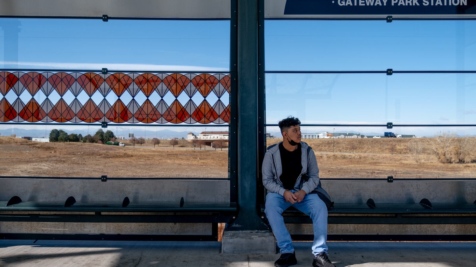 A young man, wearing a grey sweatshirt and blue jeans, waits for his train to arrive to the 40th Avenue station.