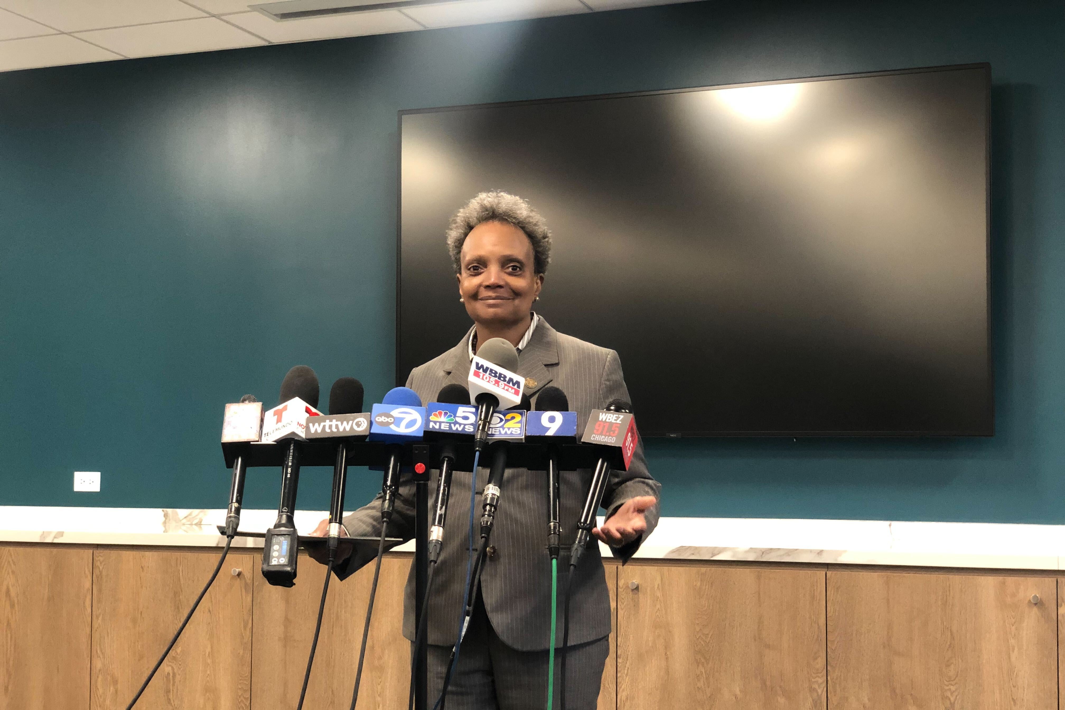 A smiling woman in a suit stands a lectern.
