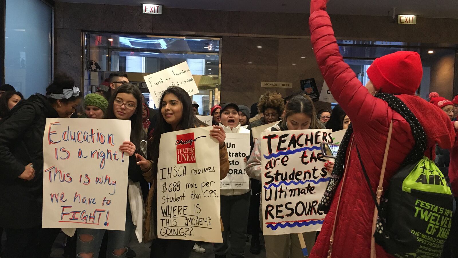 Teachers and students stand in the lobby of a building where their network is holding a board meeting.