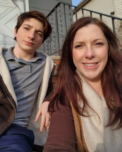 A young boy and woman sit next to each other outside on steps.