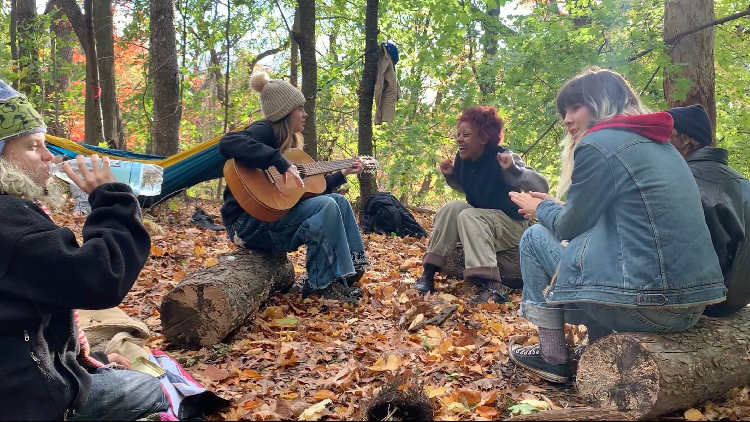 A group of teens in a park with a guitar.