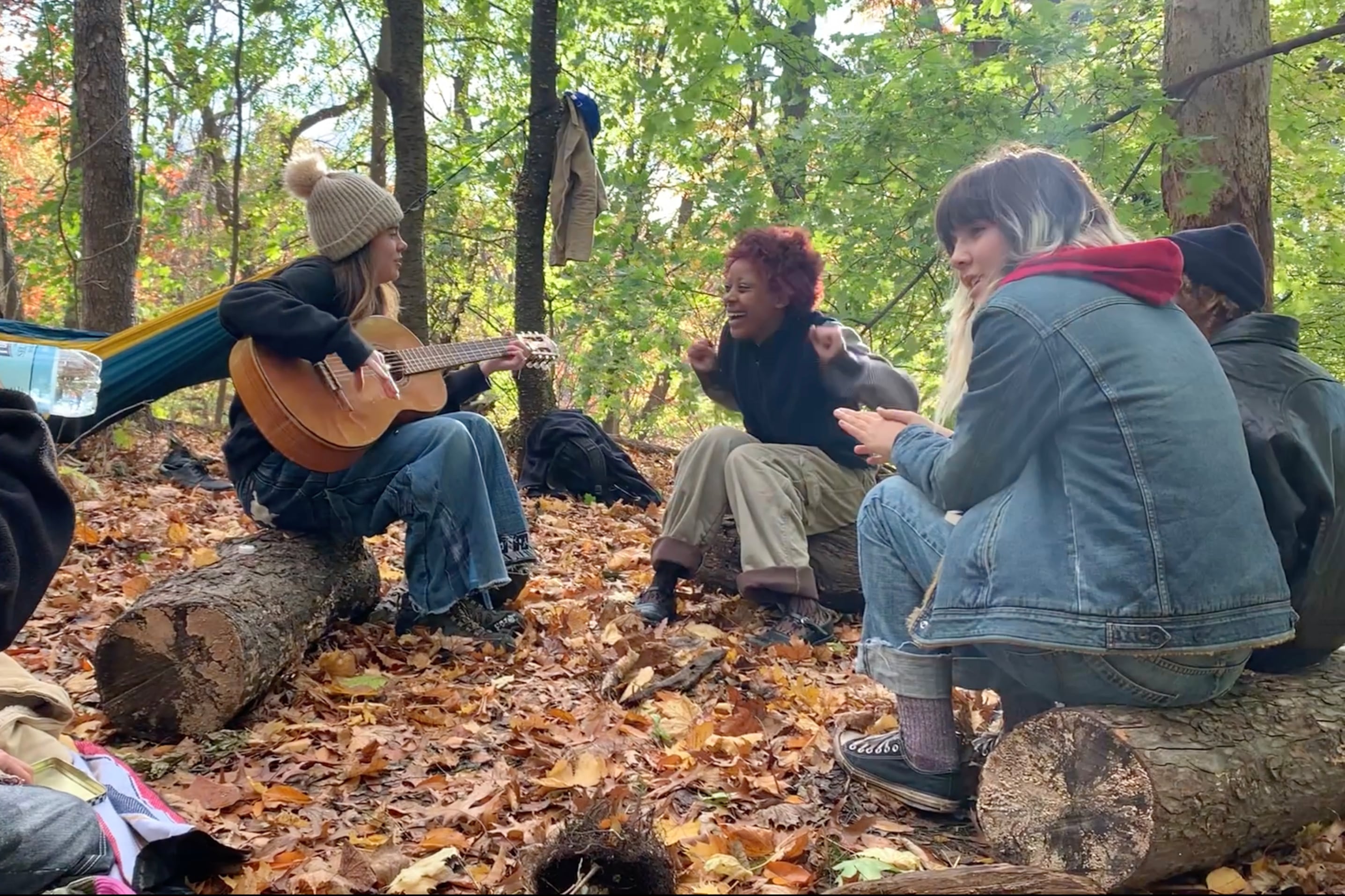 A group of teens in a park with a guitar.