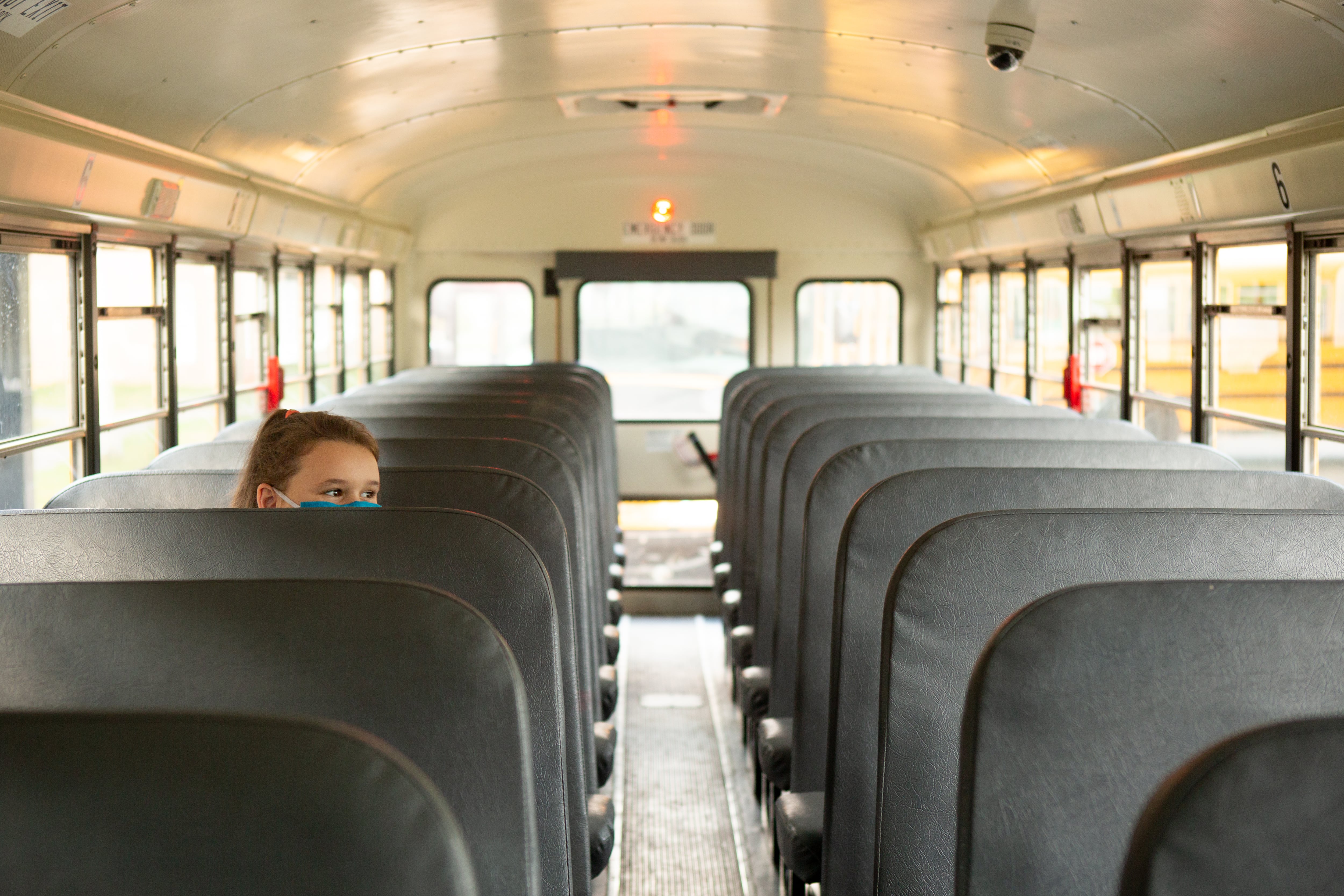 A girl waits inside a nearly empty school bus at the end of the school day.