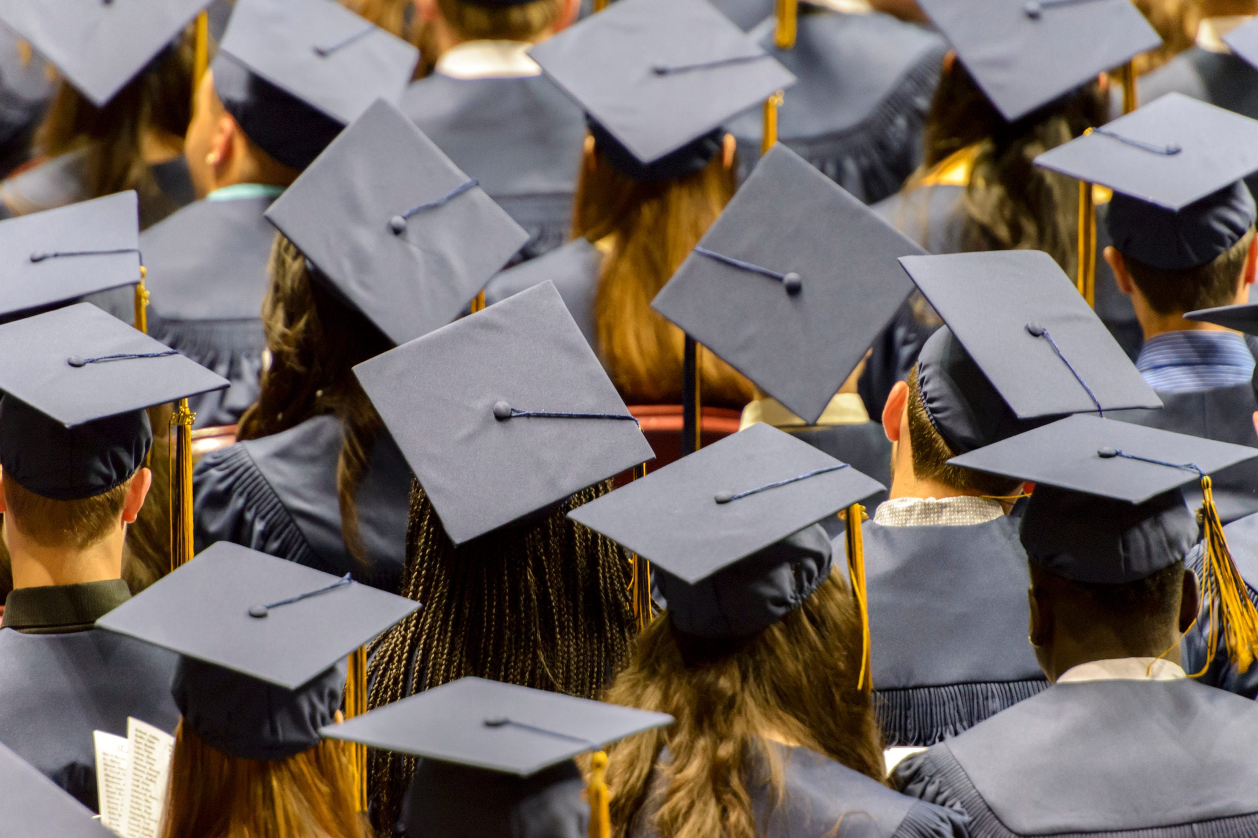 A group of students wearing black caps and gowns sit during their graduation ceremony.