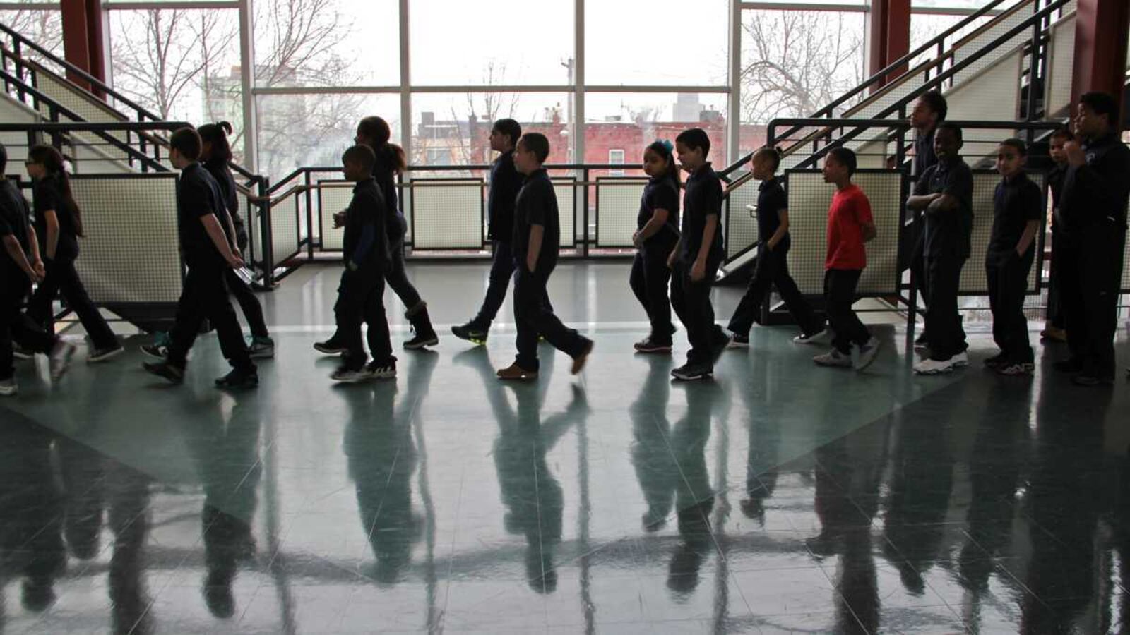 Students walk in a hallway, with their shadows visible on the floor.