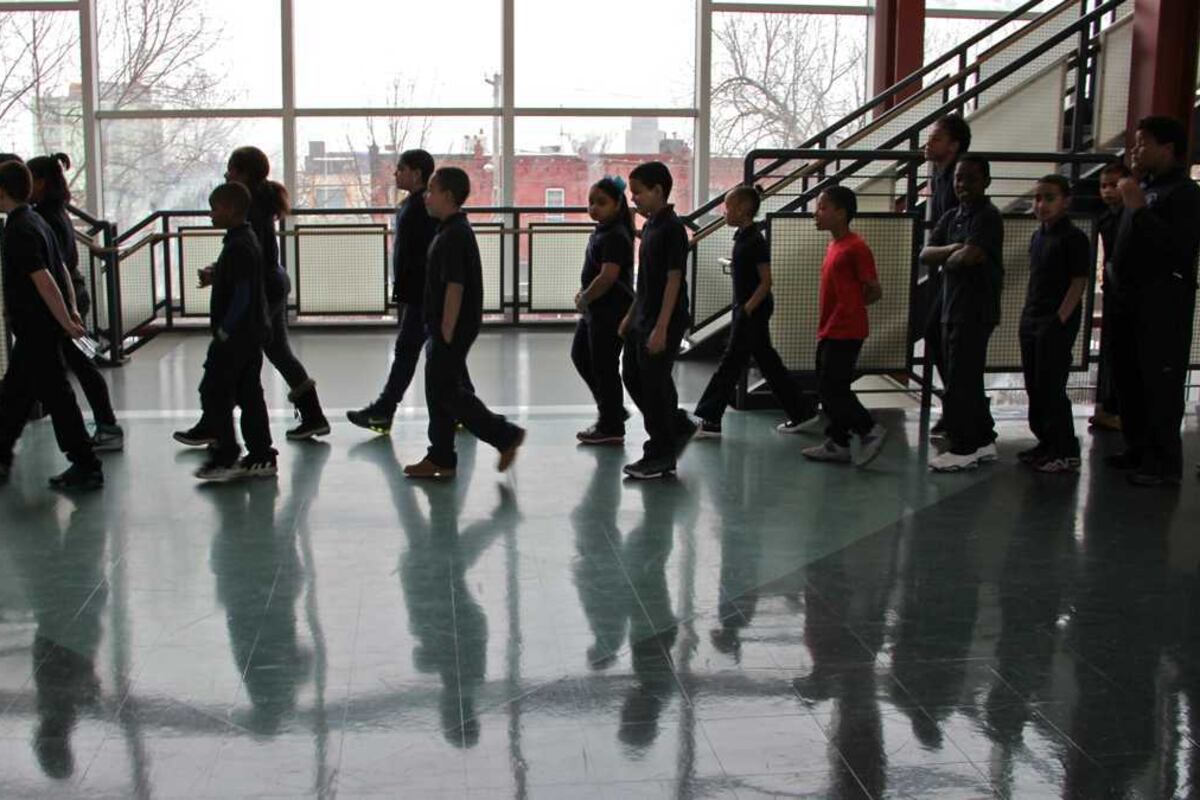 Students walk in a hallway, with their shadows visible on the floor.