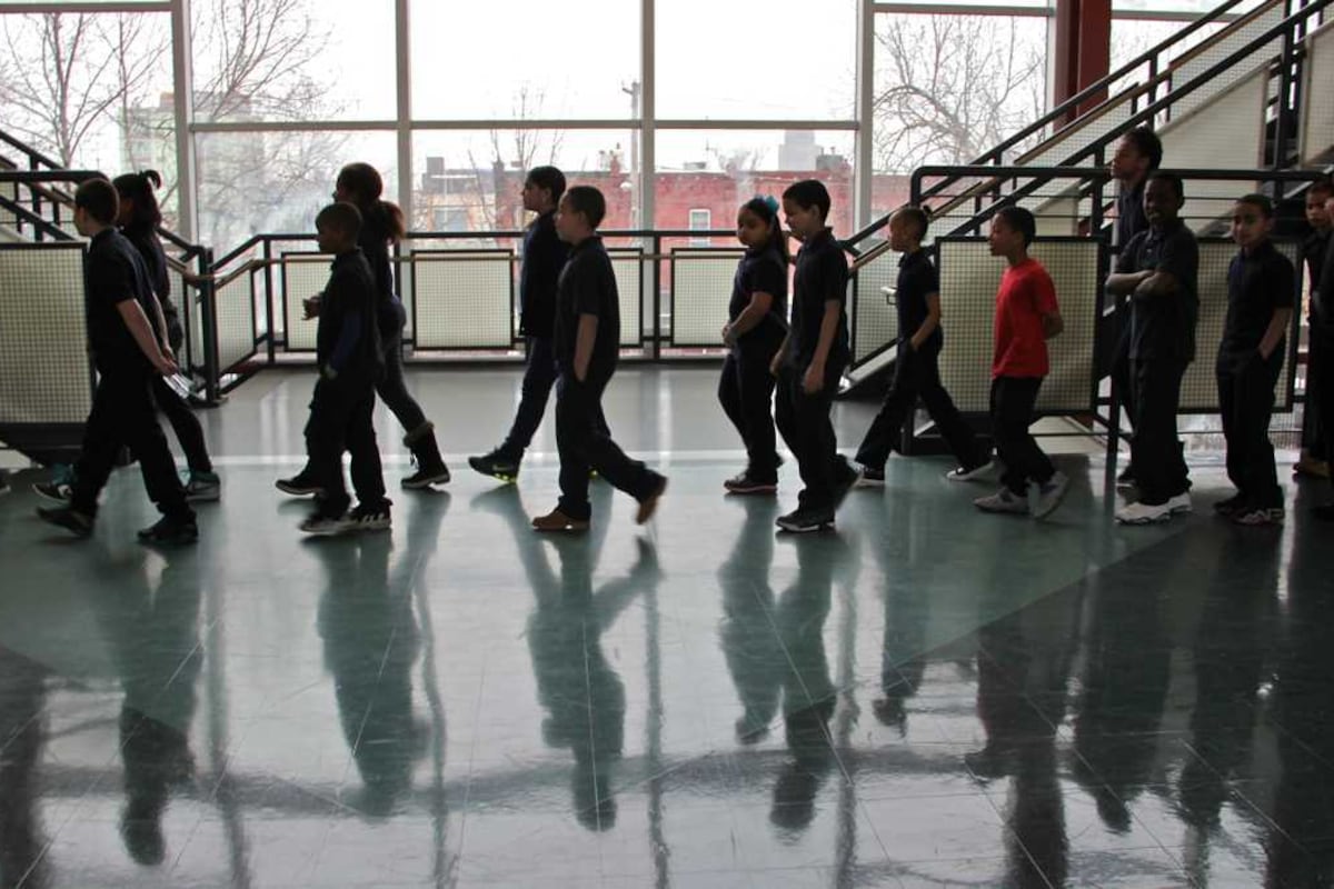Students walk in a hallway, with their shadows visible on the floor.