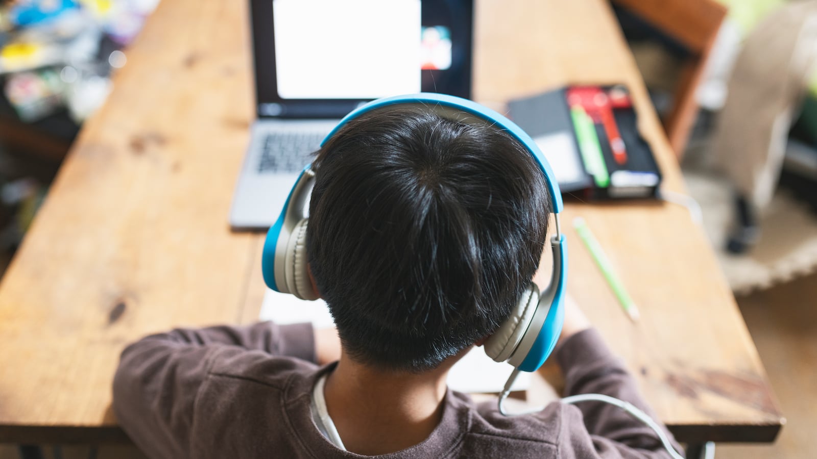 Student wearing headphones sits at a table with a laptop.