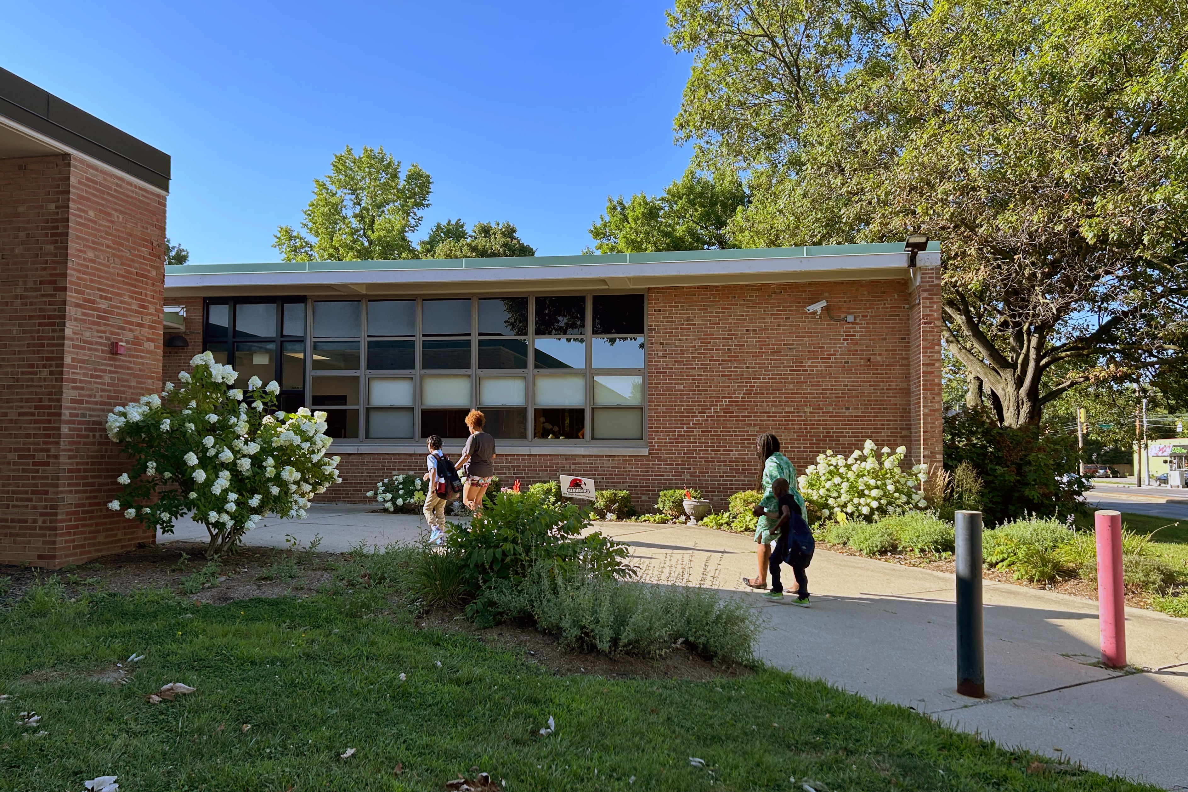 People walk on a path towards a brick building.
